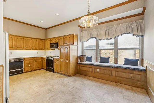 a large kitchen with stainless steel appliances a large counter top a stove and a chandelier