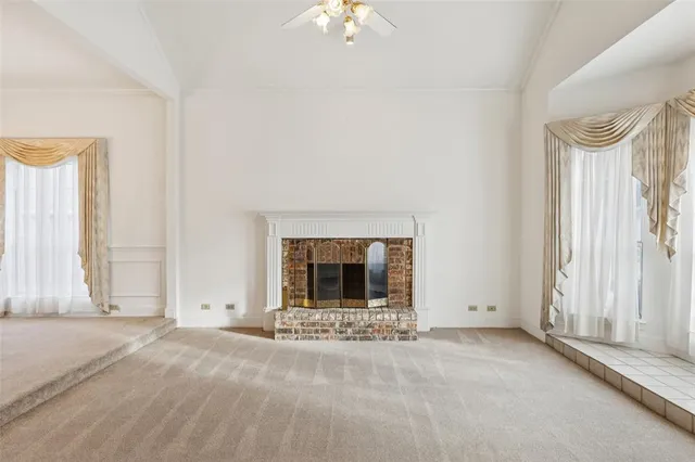 an empty room with a fireplace and large window
