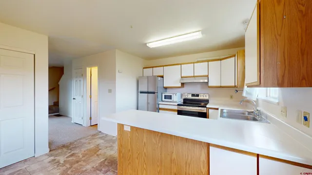 a open kitchen with stainless steel appliances granite countertop a sink dishwasher a stove and a refrigerator with wooden floor