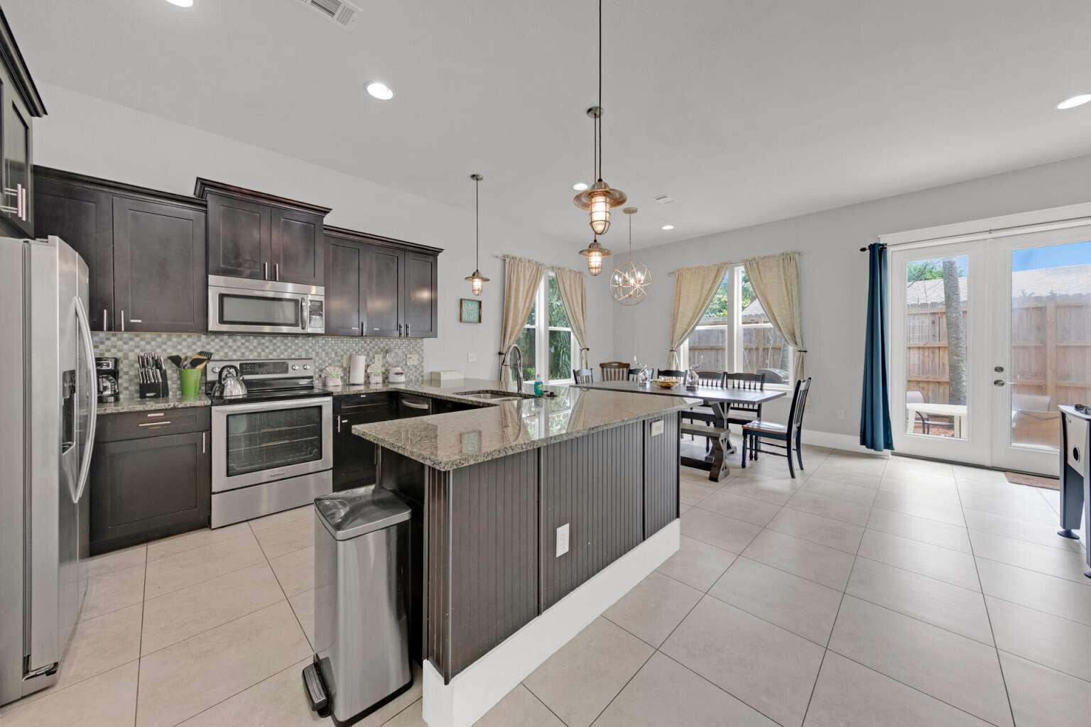 228 Miami Street Miramar Beach, FL 32550 - Photo 8 of 20 a kitchen with stainless steel appliances granite countertop a stove refrigerator a sink dishwasher a dining table and chairs with wooden floor