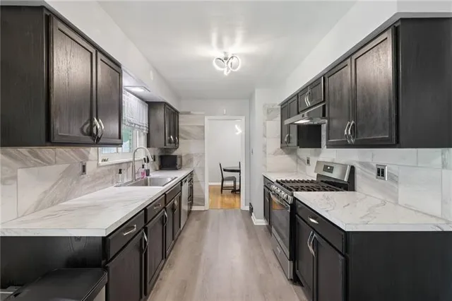 a kitchen with stainless steel appliances sink stove microwave and cabinets