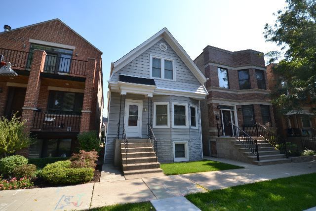 3239 North Leavitt Street, Unit 2 Chicago, IL 60618 - Photo 1 of 12 a view of a house with brick walls and a yard with plants