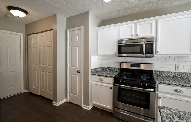 a kitchen with white cabinets and stainless steel appliances