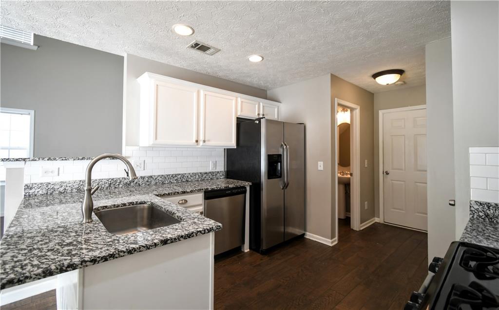 6215 Smoke Ridge Lane Cumming, GA 30041 - Photo 12 of 32 a kitchen with stainless steel appliances granite countertop a sink stove and refrigerator