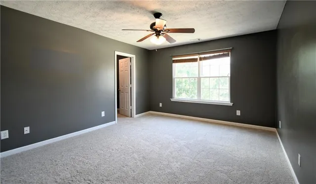 an empty room with windows and ceiling fan