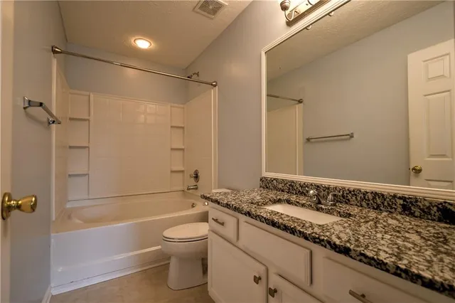 a bathroom with a granite countertop sink a toilet and shower