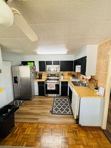 a large kitchen with a stove a refrigerator a sink dishwasher and a fireplace with wooden floor