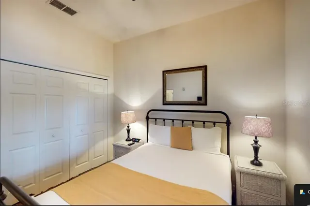 a bedroom with a bed and a potted plant on the dresser