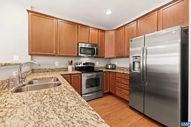 a open kitchen with granite countertop a sink dishwasher stove and cabinets with wooden floor
