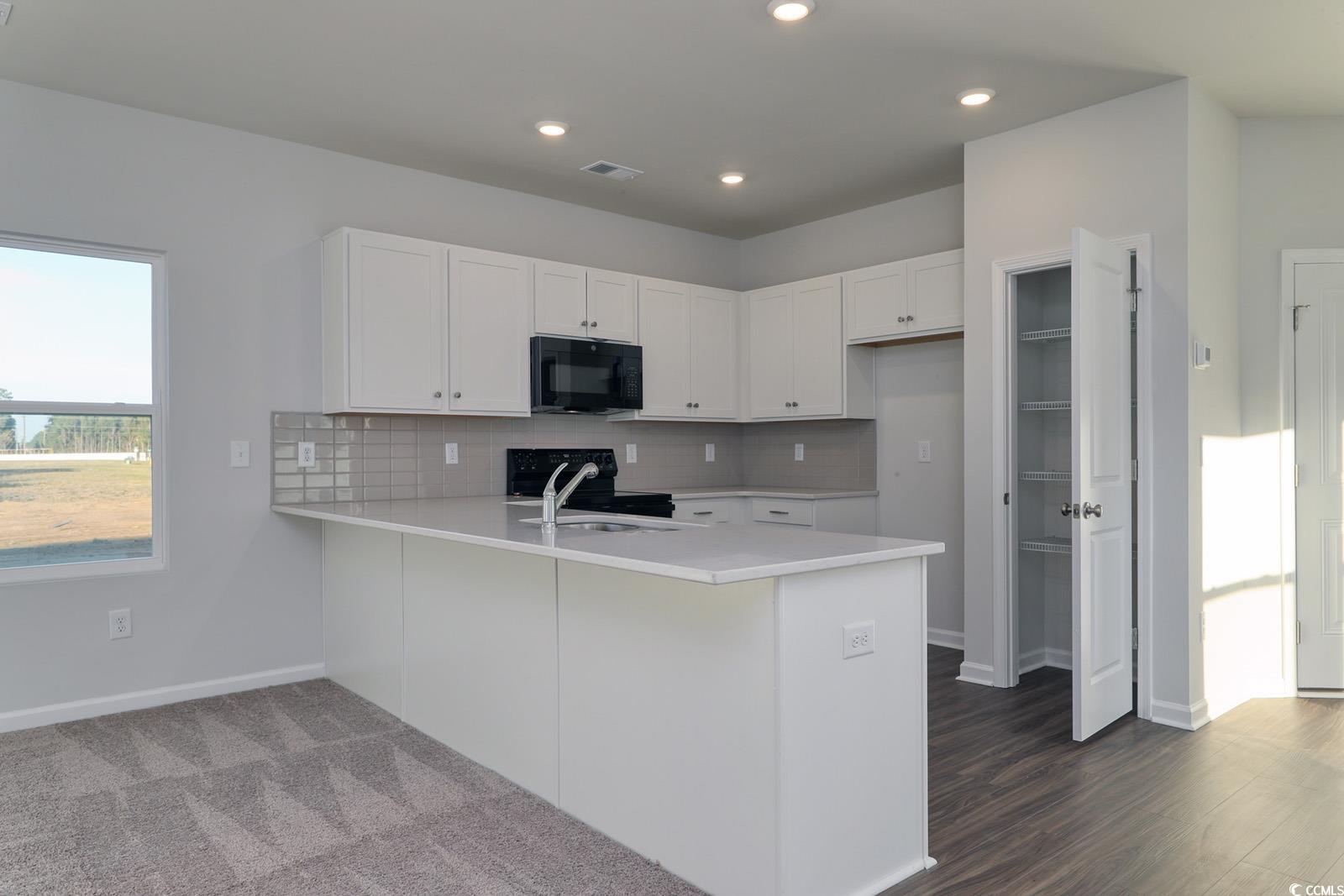1121 Hainer Place Drive Conway, SC 29526 - Photo 6 of 28 Kitchen featuring white cabinetry, a peninsula, black appliances, decorative backsplash, and light stone countertops