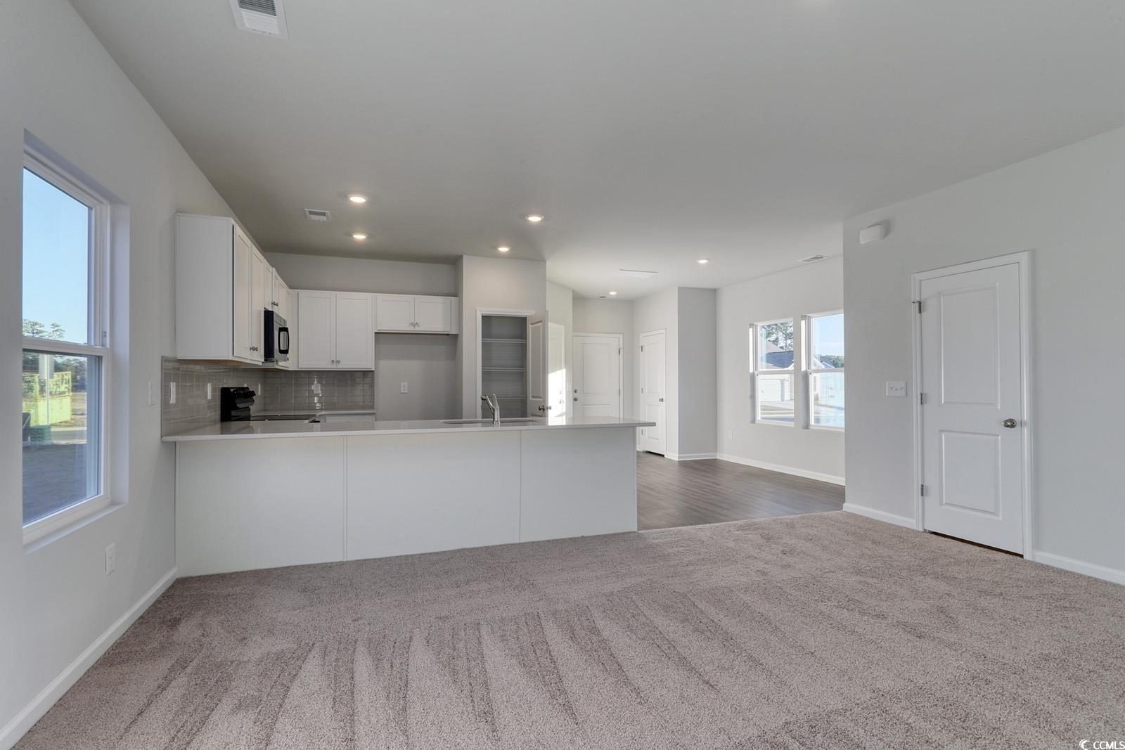1121 Hainer Place Drive Conway, SC 29526 - Photo 28 of 28 Kitchen with white cabinetry, decorative backsplash, open floor plan, dark colored carpet, and a peninsula