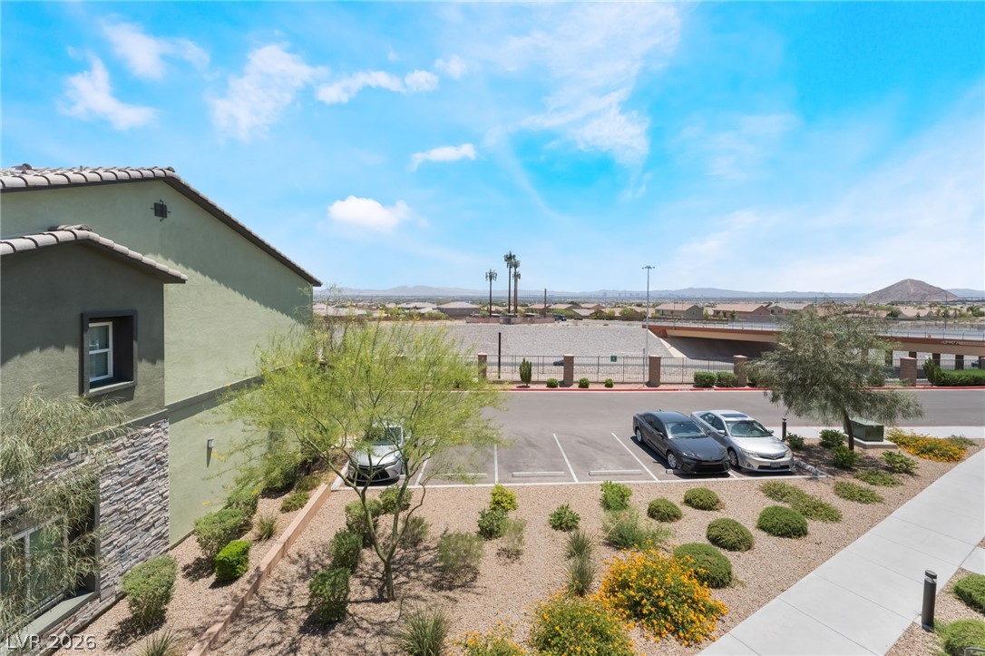 6432 Spring Jog Street Las Vegas, NV 89166 - Photo 27 of 61 A desert landscape with varied greenery and architectural interest unfolds under a wide-open, bright blue sky.
