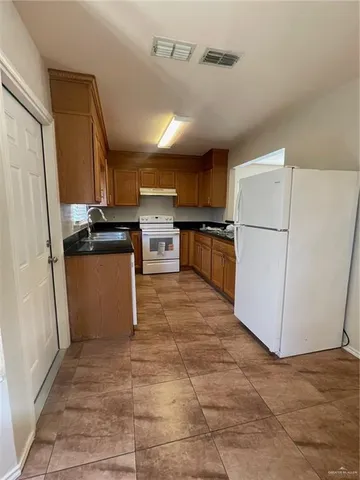 a kitchen with a refrigerator a stove top oven a sink and cabinets