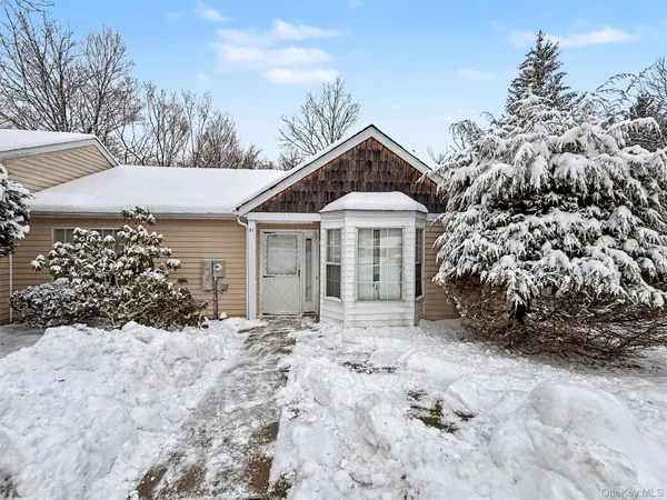a front view of a house with a yard covered with snow