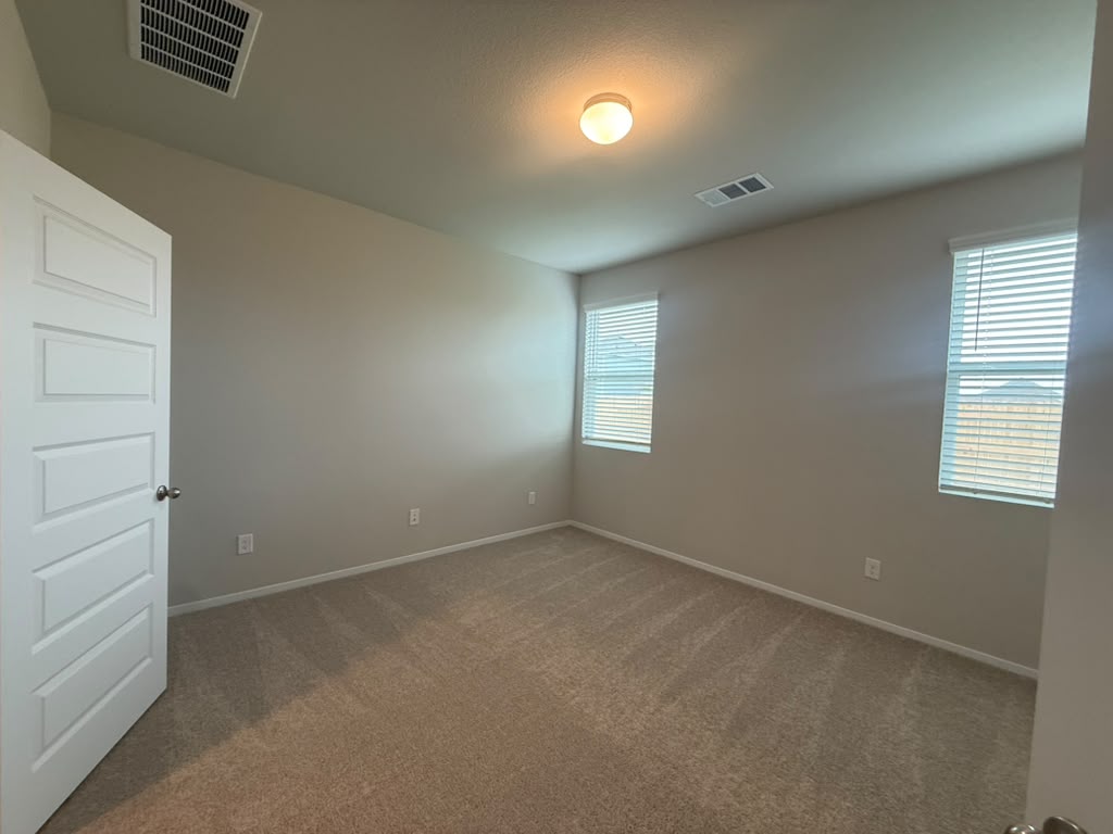 2601 Foss Road Manor, TX 78653 - Photo 23 of 40 Plush carpeting and dual windows bring comfort to this versatile secondary bedroom space.