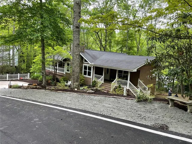 a view of a wooden house with a yard and large trees