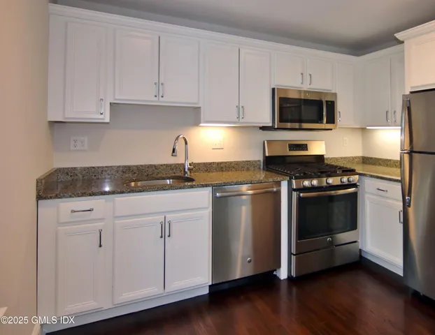 a kitchen with granite countertop white cabinets and stainless steel appliances