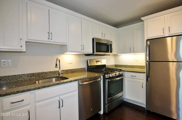 a kitchen with granite countertop white cabinets and stainless steel appliances