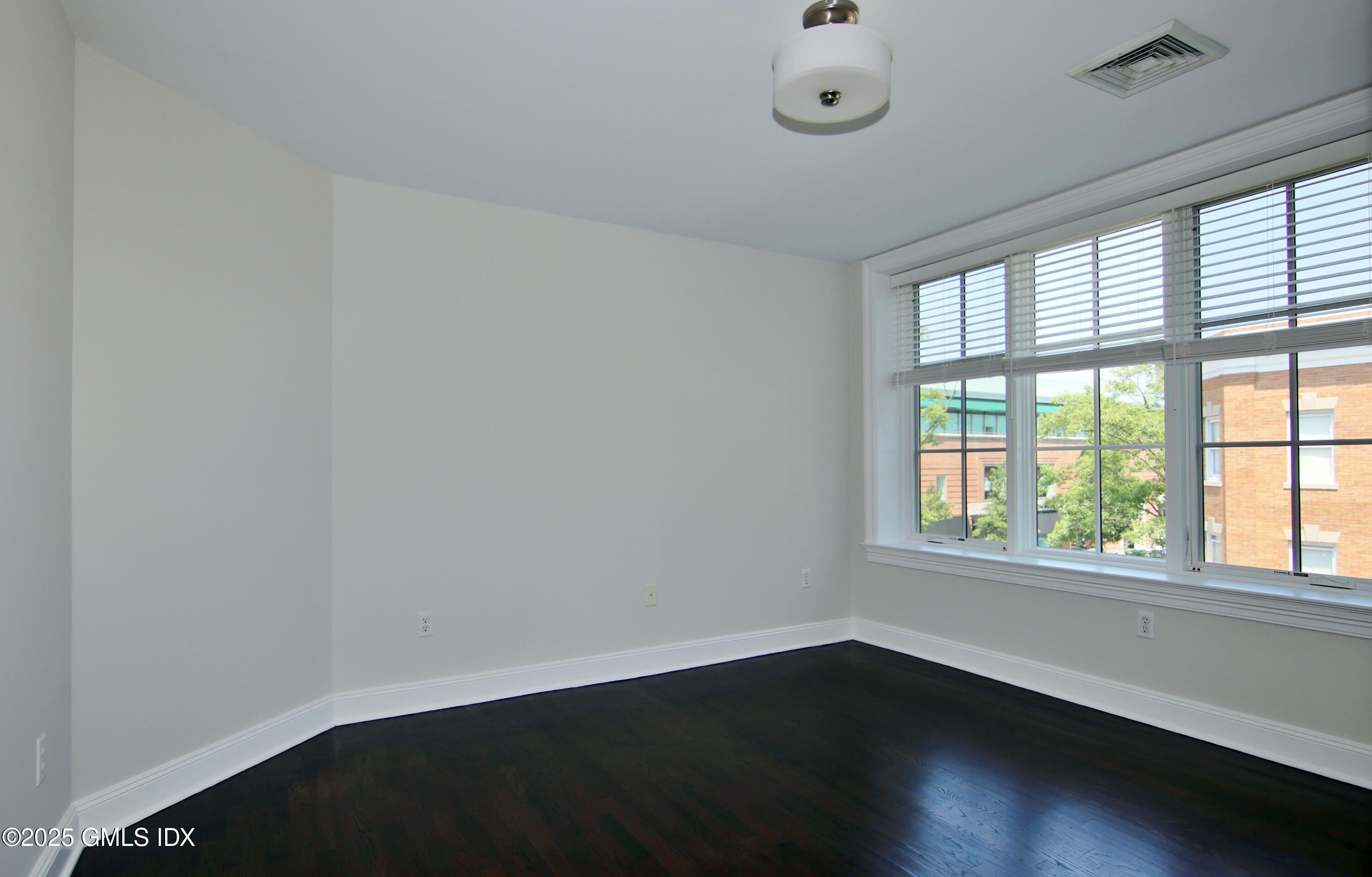 2 East Elm Street, Unit 35 Greenwich, CT 06830 - Photo 9 of 21 an empty room with wooden floor and windows