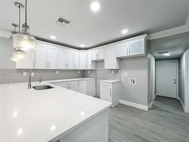 a large white kitchen with wooden floors and white cabinets