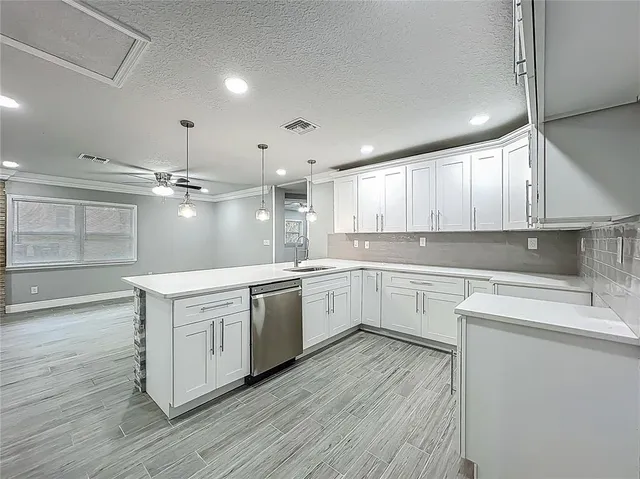 a kitchen with a sink dishwasher a stove and white cabinets with wooden floor