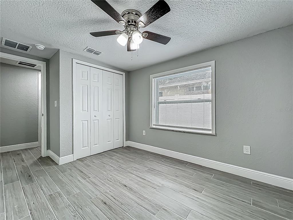 1414 Beaver Street Orlando, FL 32806 - Photo 19 of 43 an empty room with wooden floor chandelier fan and windows