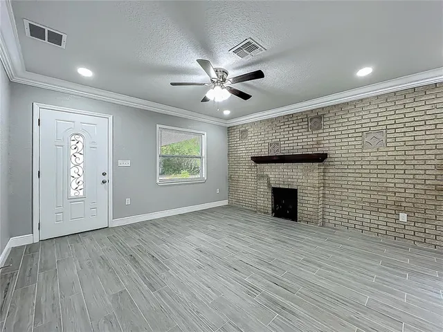 a view of an empty room with wooden floor and a fireplace