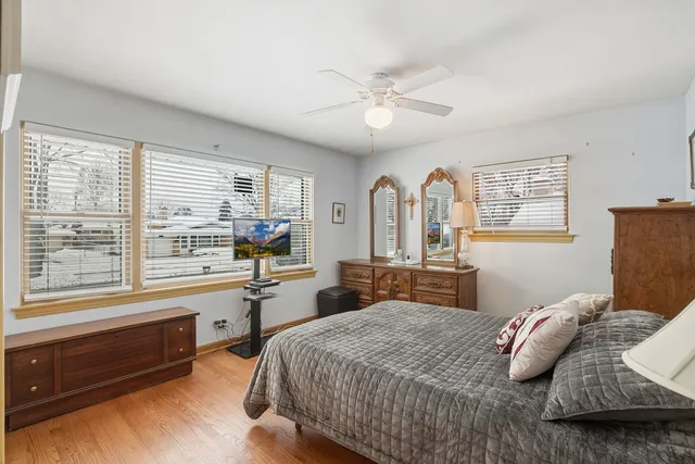 a bedroom with a bed and a large window with wooden floor