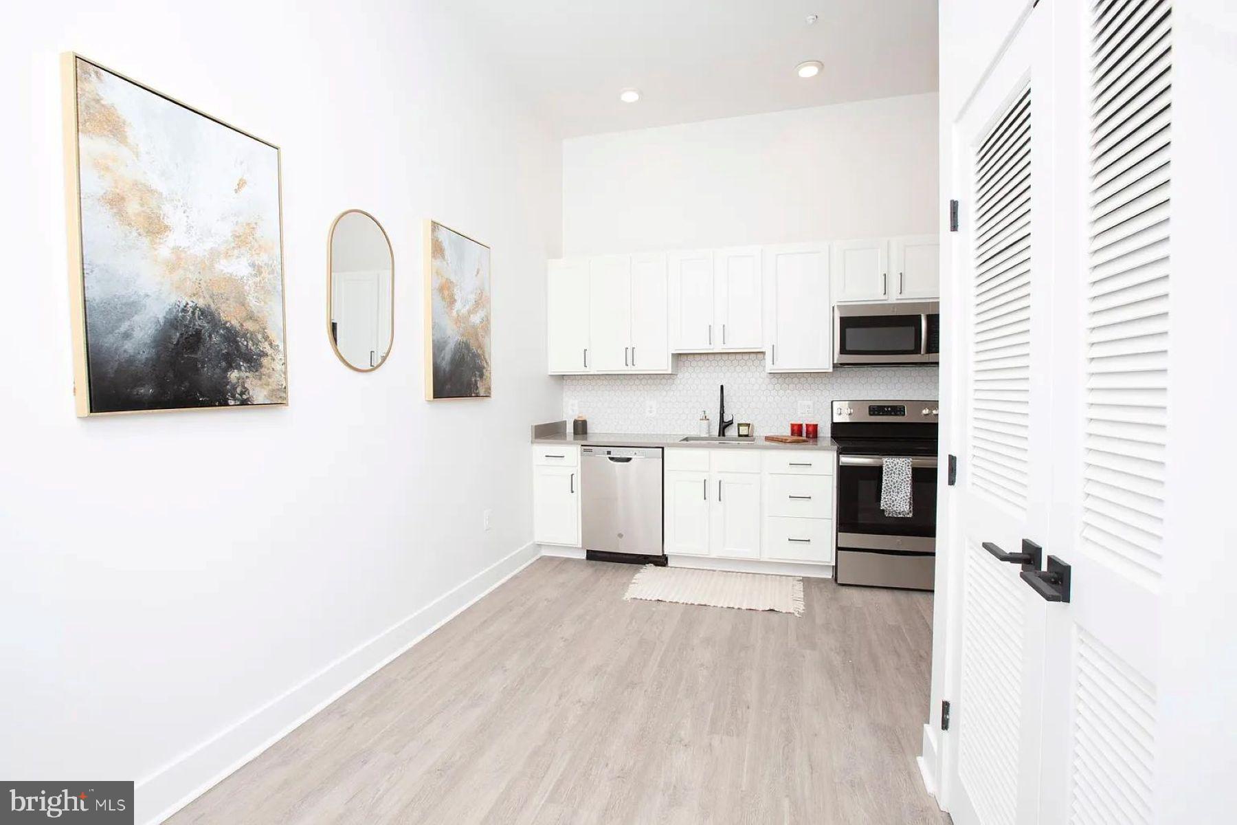1742 Fleet Street, Unit 301 Baltimore, MD 21231 - Photo 3 of 20 a white kitchen with a sink a window and stainless steel appliances