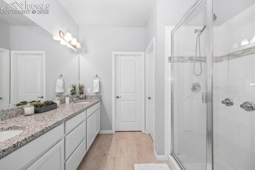 15446 West 64th Loop, Unit D Arvada, CO 80007 - Photo 12 of 22 a bathroom with a granite countertop sink a shower and a mirror
