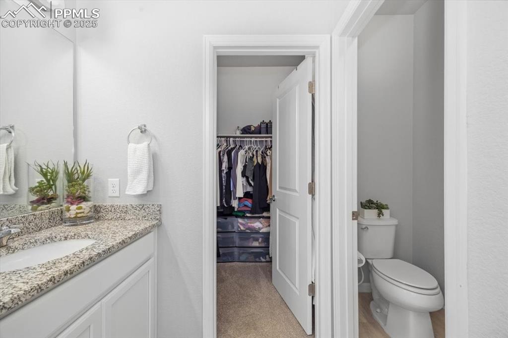 15446 West 64th Loop, Unit D Arvada, CO 80007 - Photo 13 of 22 a bathroom with a granite countertop sink and a toilet