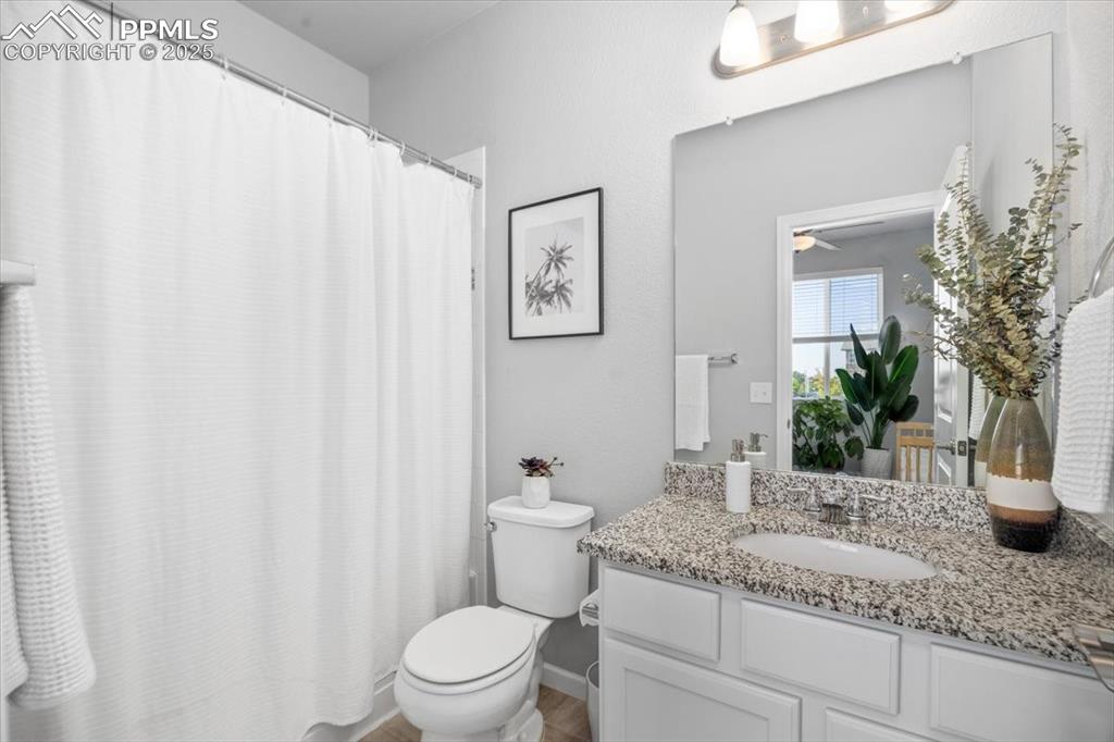 15446 West 64th Loop, Unit D Arvada, CO 80007 - Photo 16 of 22 a bathroom with a granite countertop sink a toilet and mirror