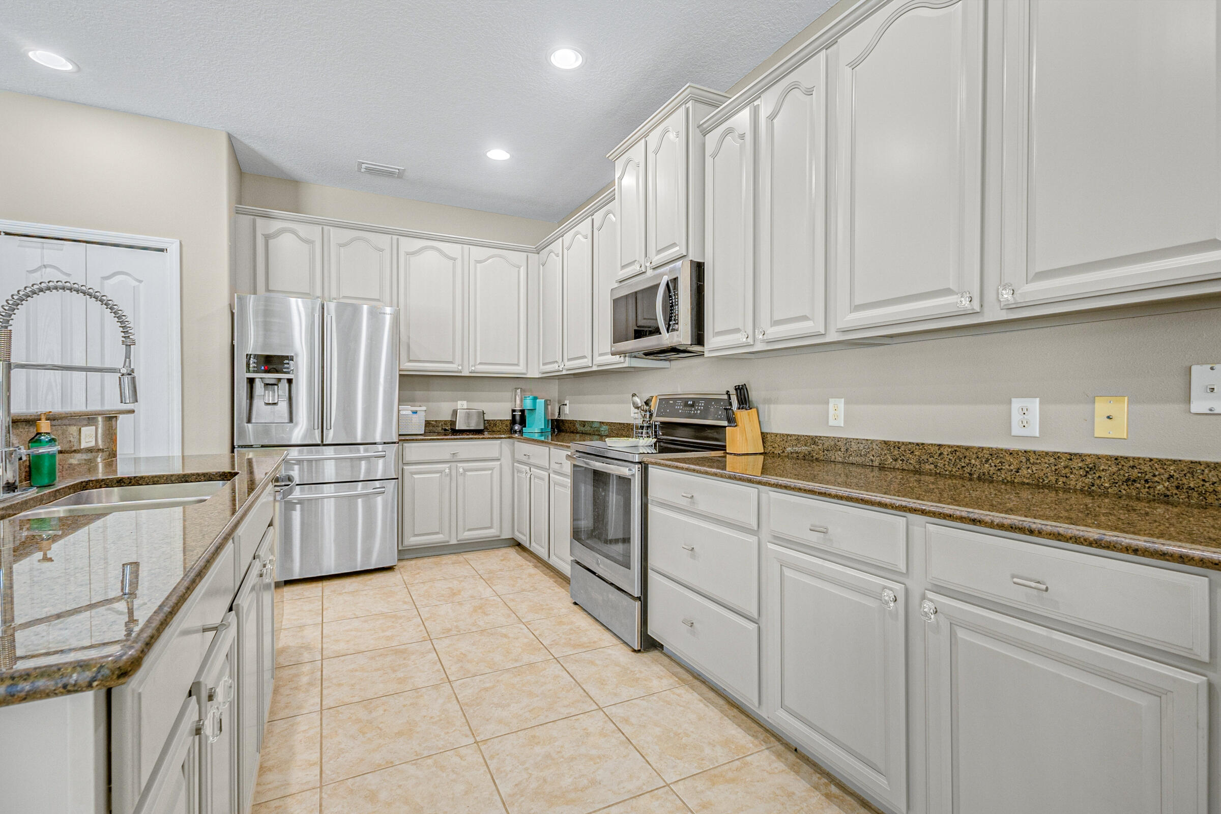 6002 Goleta Circle Melbourne, FL 32940 - Photo 6 of 45 a kitchen with stainless steel appliances granite countertop a refrigerator sink and cabinets