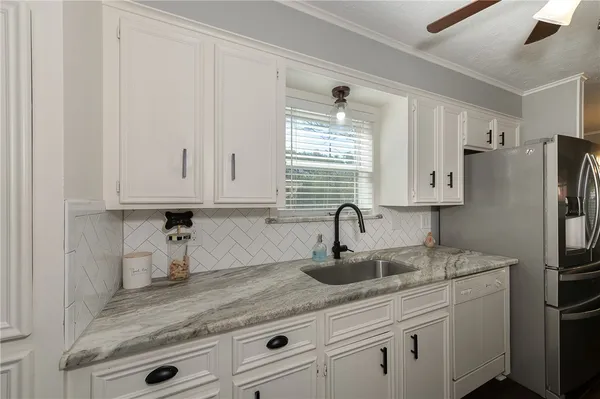 a kitchen with stainless steel appliances granite countertop white cabinets sink and refrigerator