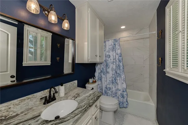 a bathroom with a sink a toilet a mirror and shower
