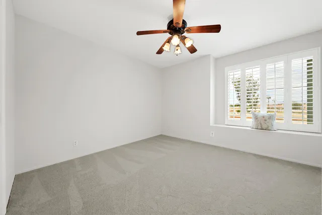 an empty room with windows and chandelier fan