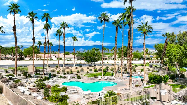a view of a swimming pool with a lawn chairs under an umbrella