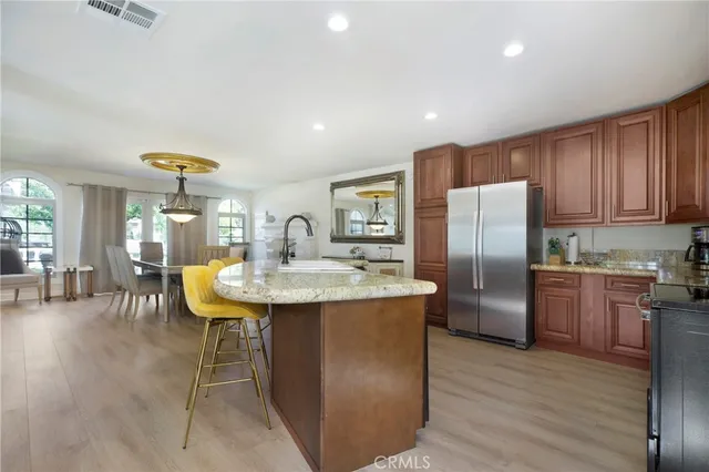 a kitchen with stainless steel appliances granite countertop a sink a stove a refrigerator cabinets and wooden floor