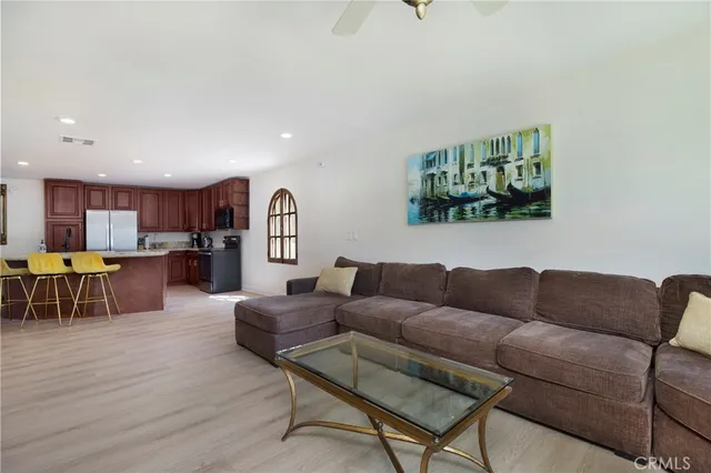 a living room with furniture kitchen view and a wooden floor