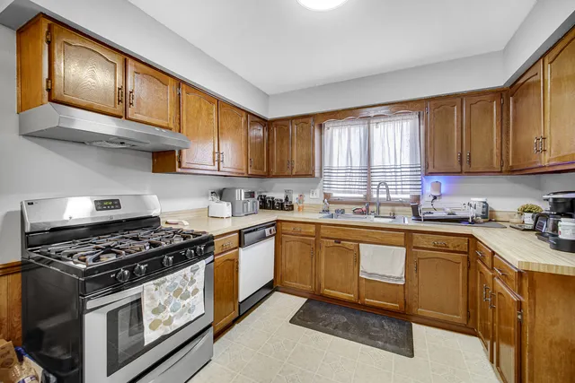 a kitchen with stainless steel appliances granite countertop a stove a sink dishwasher and cabinets with wooden floor