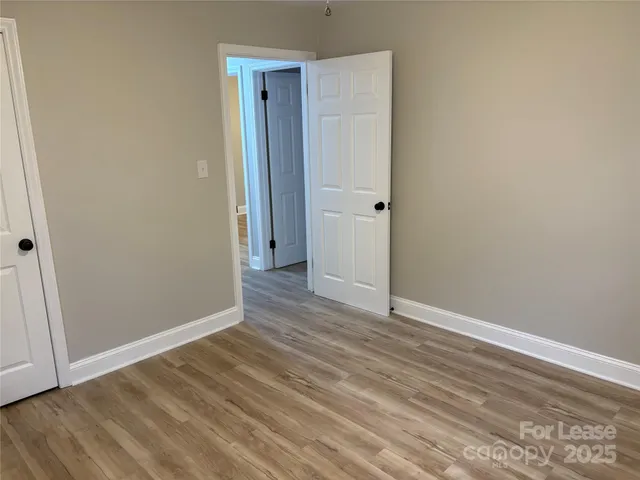 a view of an empty room with wooden floor and closet