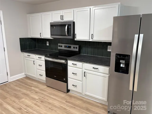 a kitchen with stainless steel appliances white cabinets and a refrigerator