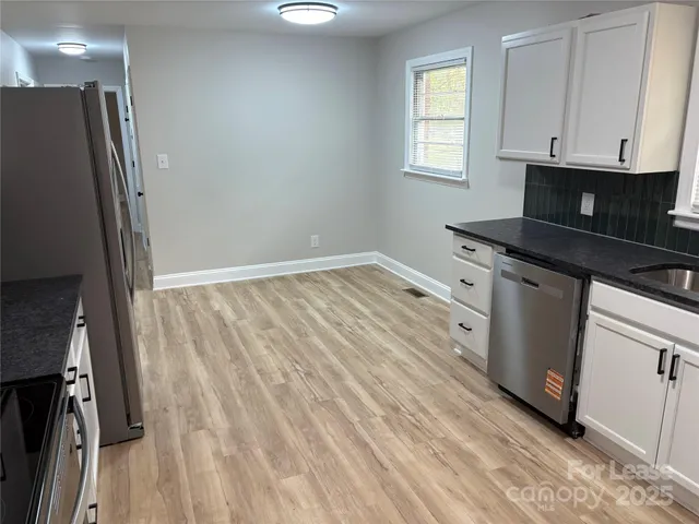 a kitchen with granite countertop a sink cabinets and stainless steel appliances