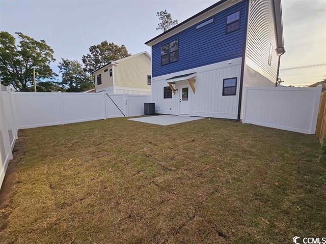 Tbd 67th Avenue North Myrtle Beach, SC 29572 - Photo 19 of 31 Back of property at dusk featuring a fenced backyard, central air condition unit, a lawn, a gate, and a patio area
