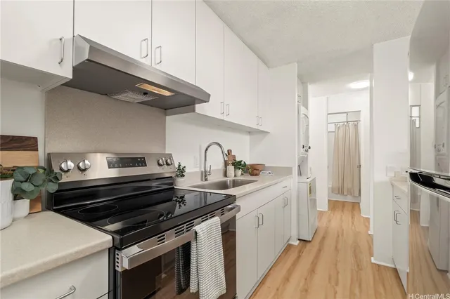 a kitchen with stainless steel appliances a sink dishwasher stove and white cabinets with wooden floor