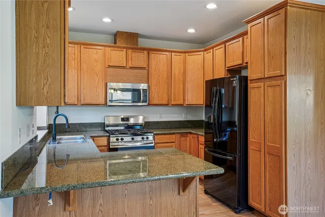 a kitchen with stainless steel appliances granite countertop a refrigerator a stove top oven a sink and dishwasher