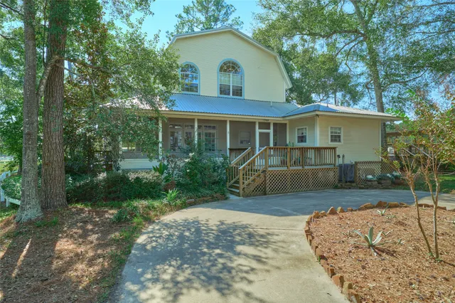 a view of a house with a yard plants and large tree