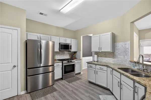 a kitchen with a refrigerator sink and wooden floor
