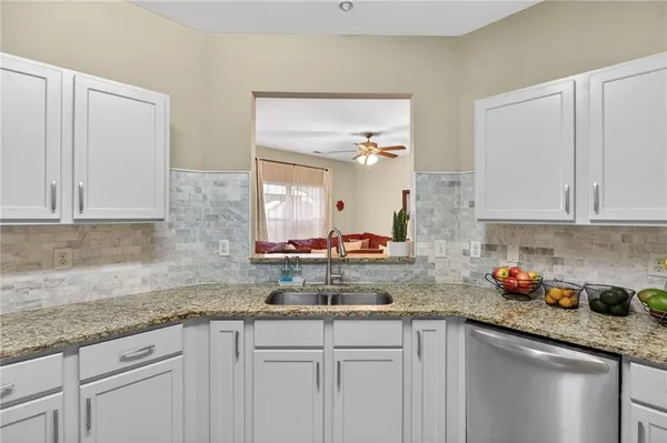 a kitchen with stainless steel appliances granite countertop a sink and cabinets with wooden floor