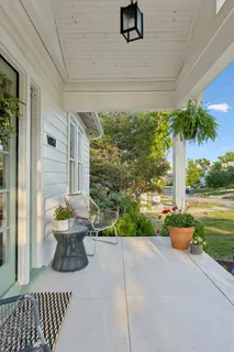 a porch with a table and chairs and potted plants